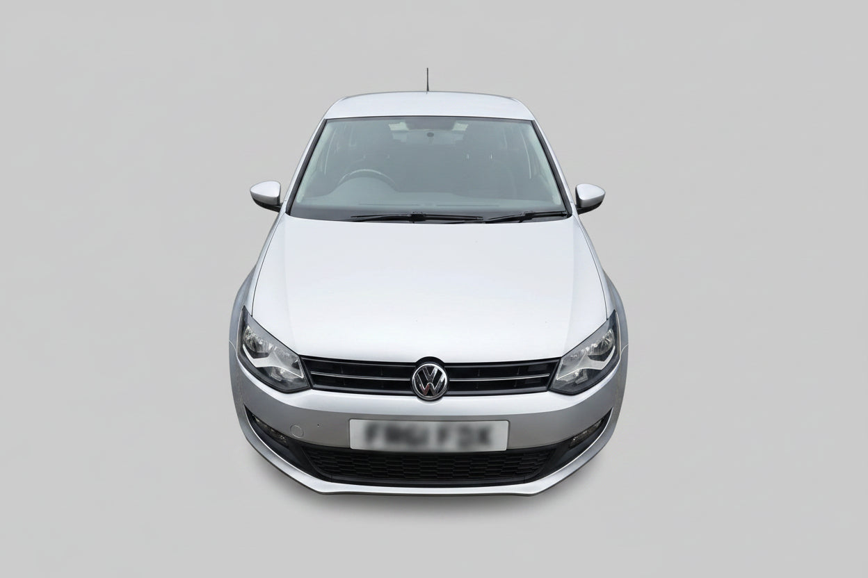 A silver Volkswagen Polo hatchback parked outdoors on a dirt lot, showing the front grille, headlights, and front license plate.